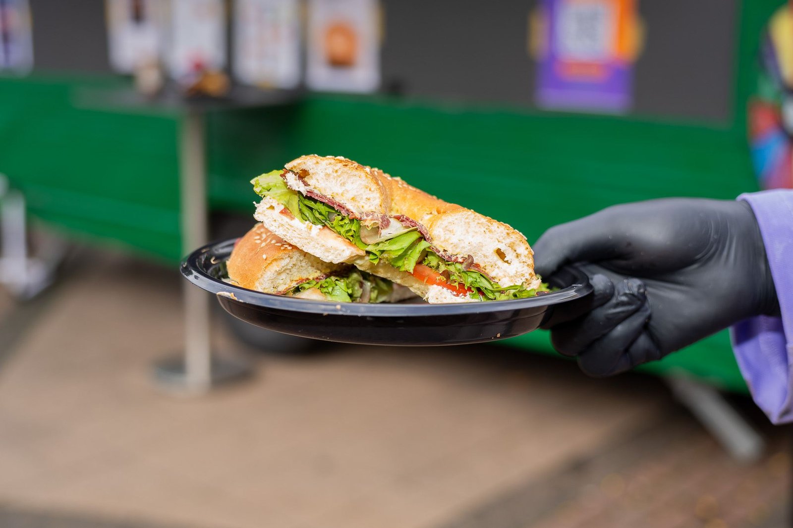 Aufgeschnittener Bagel mit Frischkäse, Salat, Tomate und Pastirma auf einem Teller