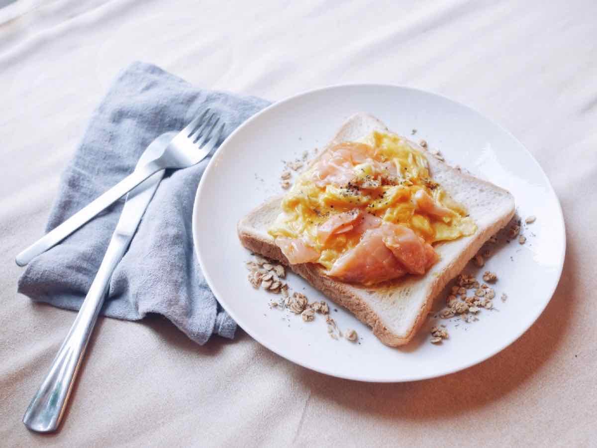 Sandwich mit Rührei und Lachs auf einem hellen Teller